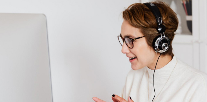 Woman speaking to someone over video conferencing, wearing headphones