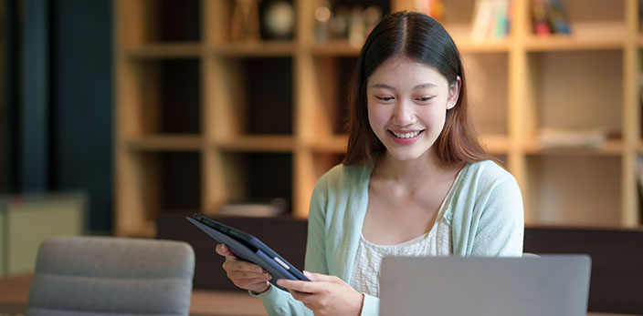 asian woman smiling while using laptop