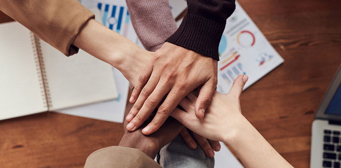 diverse team joining hands for a group huddle