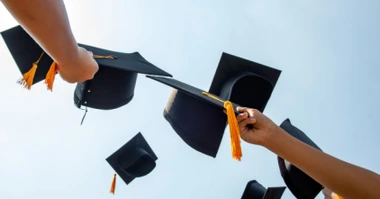 Colleage graduates holding their graduation caps